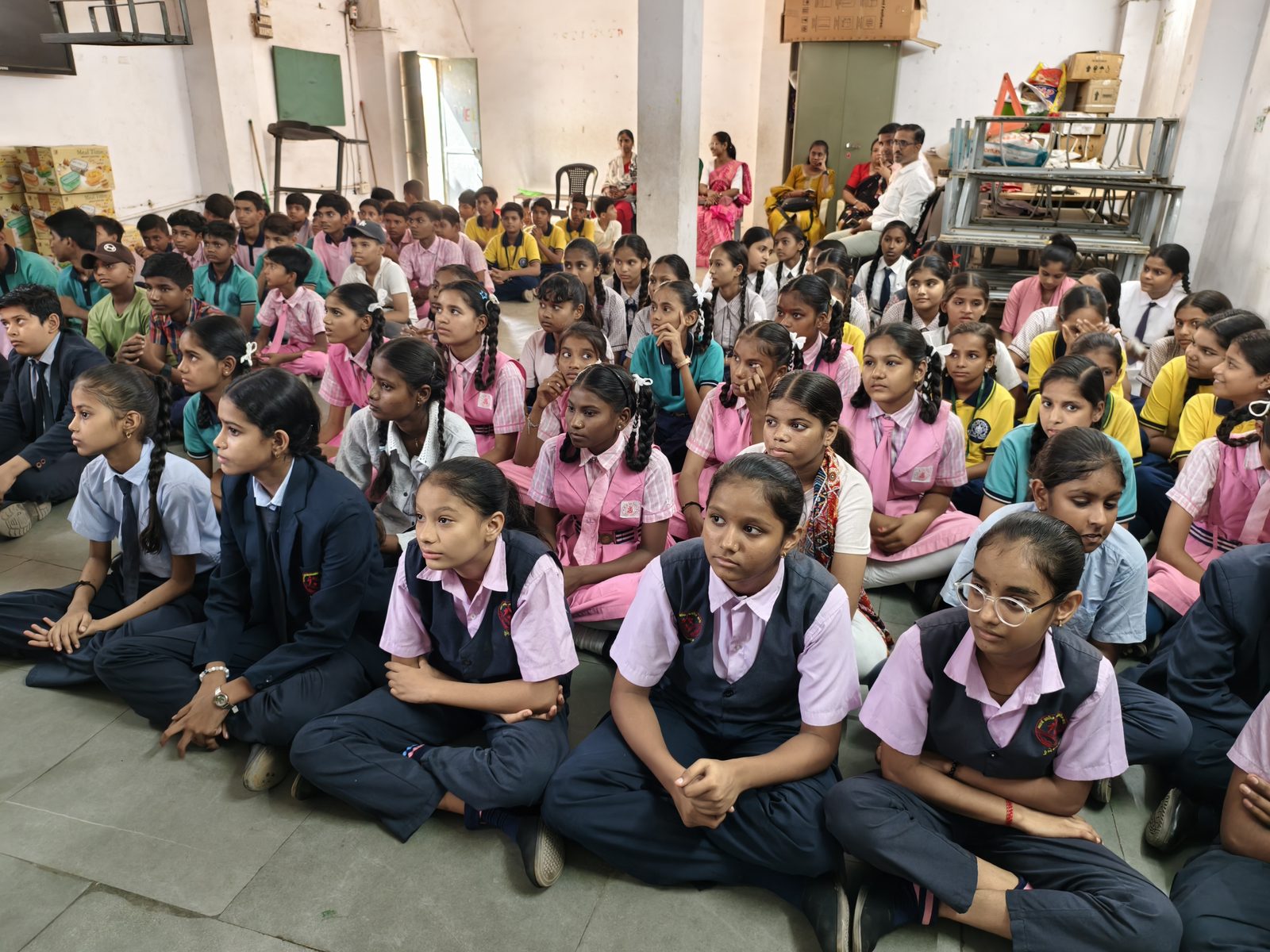 Students from several partner schools seated together at a school assembly.