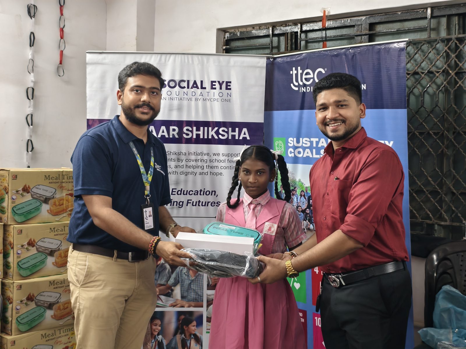 A student receiving a school kit from Social Eye Foundation and TTEC India representatives.